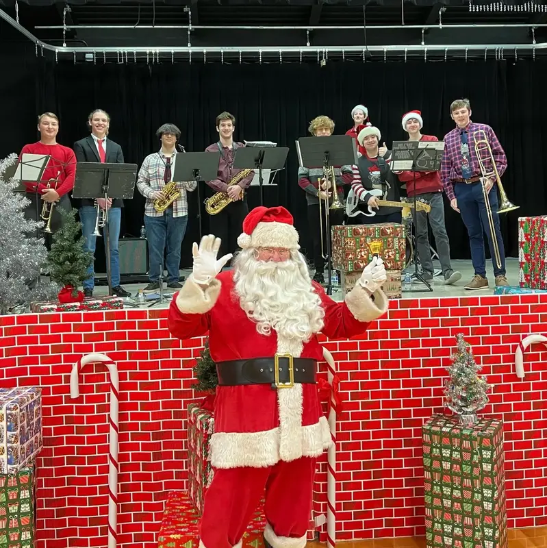 Scholarsjazz on stage at a holiday event with Santa waving in front of the band